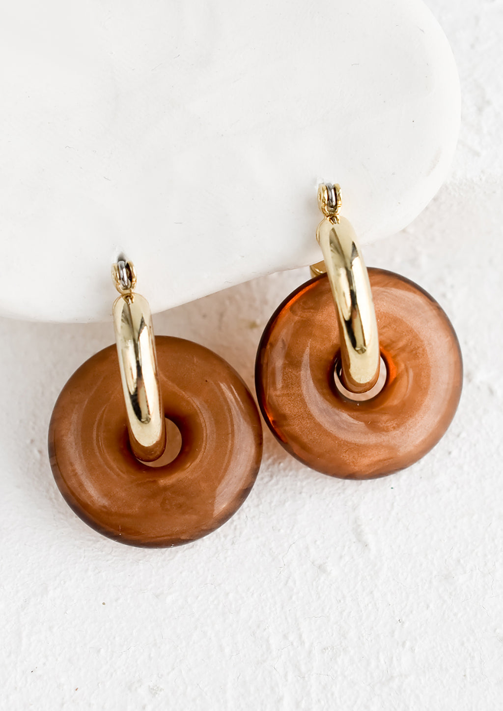 Coffee: A pair of brown resin donut shaped charms on gold hoop earrings.