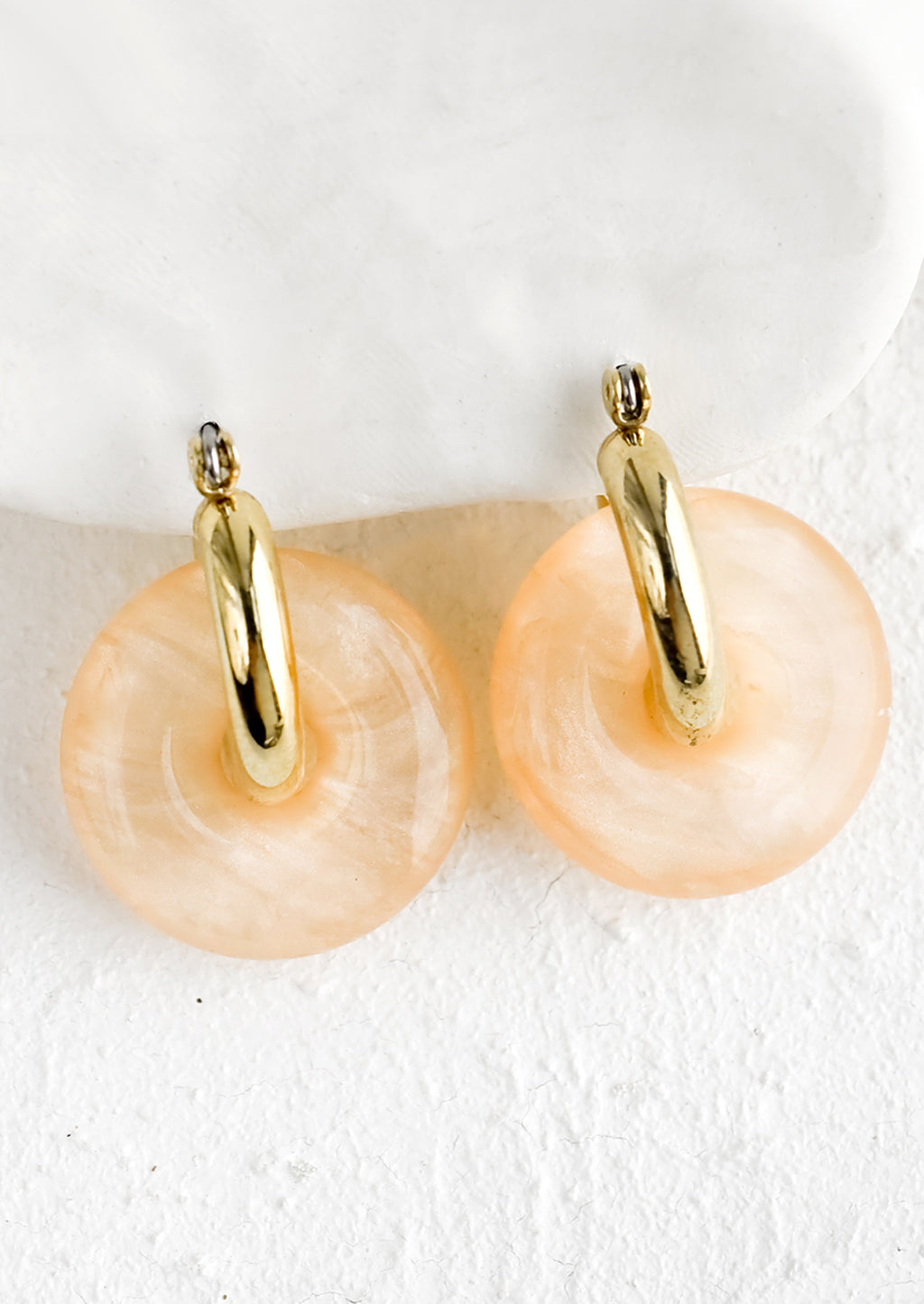 Peach: A pair of peach resin donut shaped charms on gold hoop earrings.