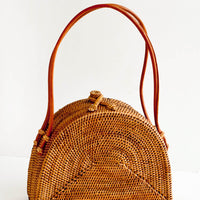 1: Half-oval shaped, structured handbag made from smoked rattan. Tanned leather carrying handles.