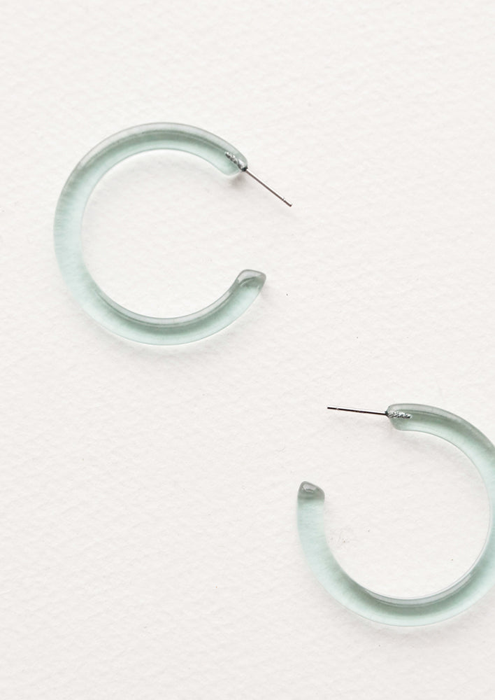 Three quarter hoop earrings in translucent aqua blue acetate.
