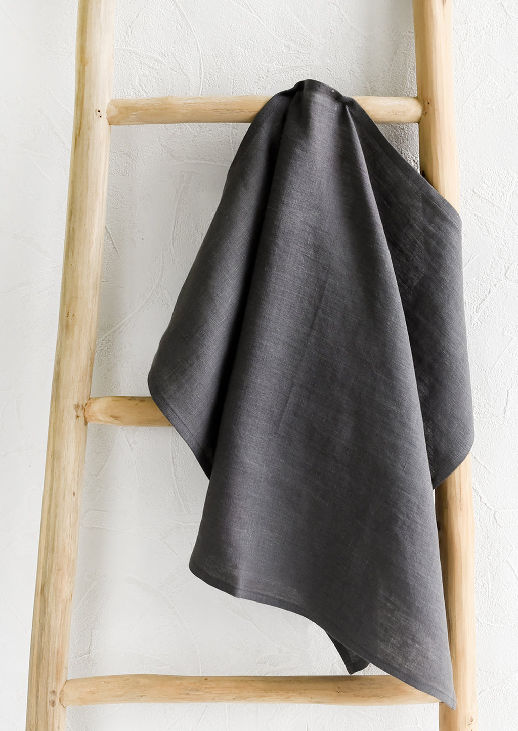 Charcoal: A charcoal linen tea towel draped on a wooden ladder.