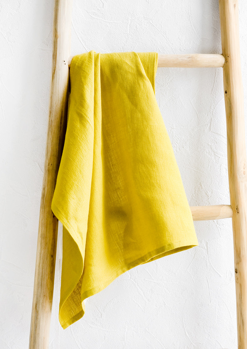 Chartreuse: A chatreuse linen tea towel draped on a wooden ladder.