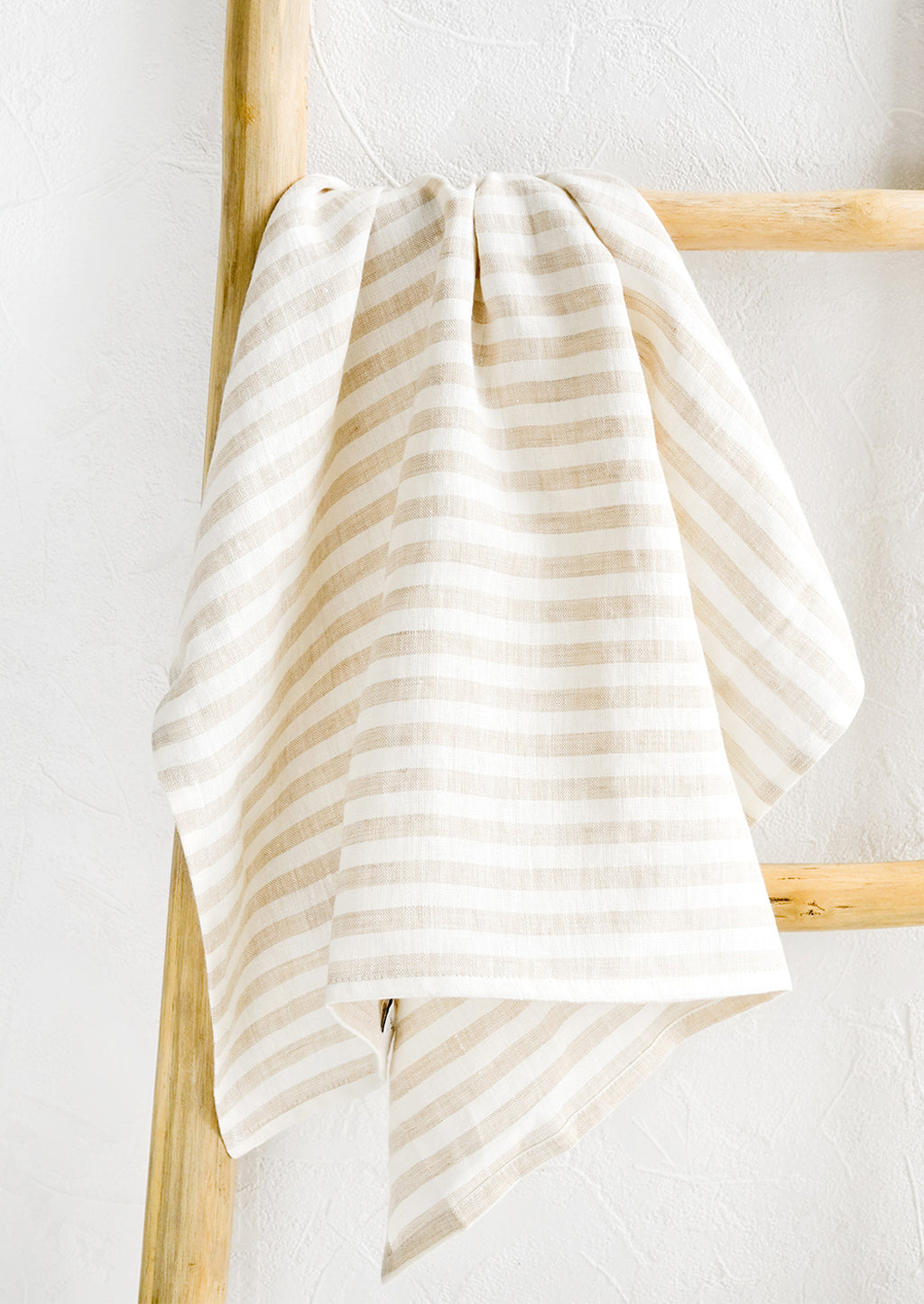 Natural Stripe: A tan striped linen tea towel draped on a wooden ladder.