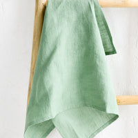 Menthe: A menthe green linen tea towel draped on a wooden ladder.