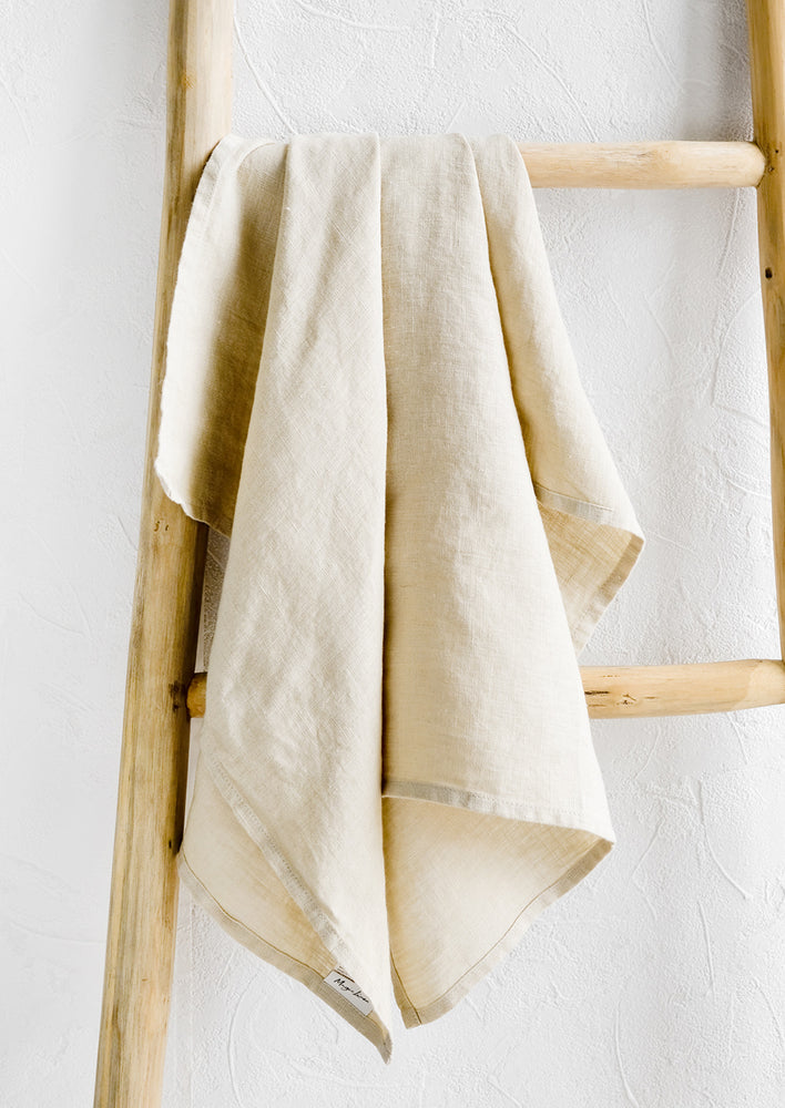 Flax: A natural linen tea towel draped on a wooden ladder.