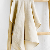 Flax: A natural linen tea towel draped on a wooden ladder.