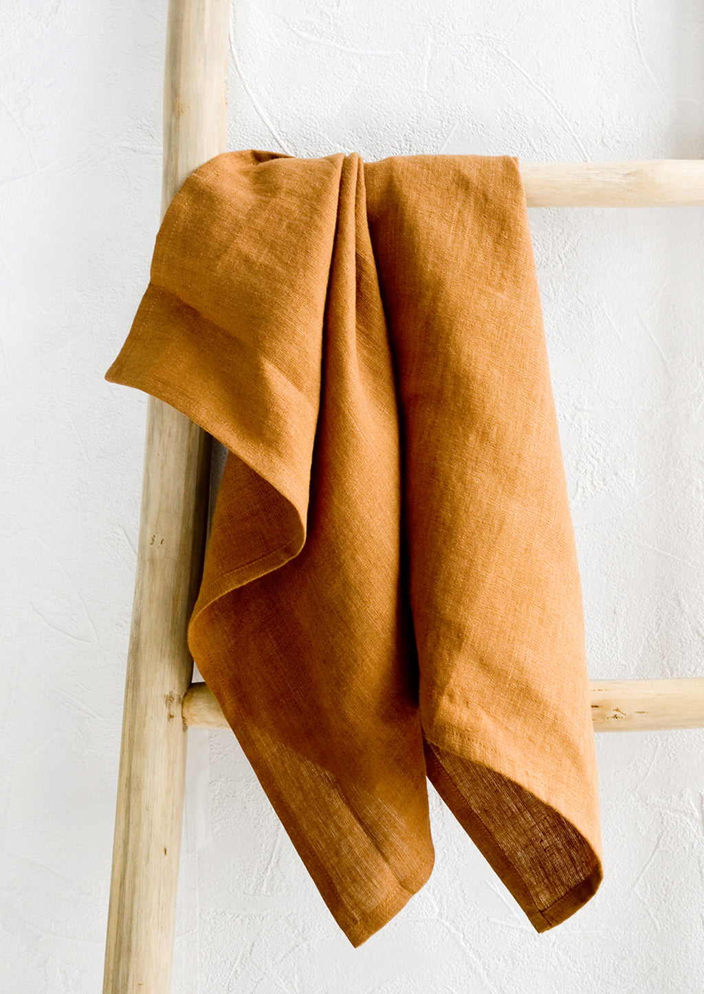 Whiskey: A whiskey brown linen tea towel draped on a wooden ladder.