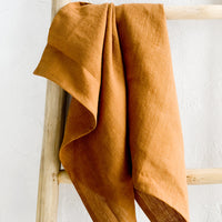 Whiskey: A whiskey brown linen tea towel draped on a wooden ladder.