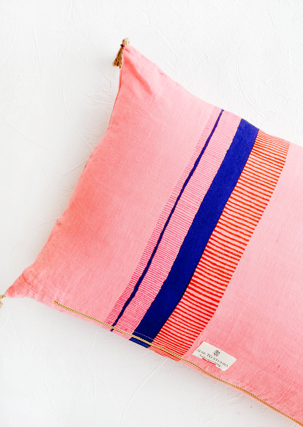 3: Backside of decorative pink linen throw pillow, block printed stripe detail and exposed metal zipper