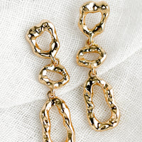 Gold: A pair of gold abstract shape drop earrings with melted metal look.