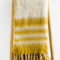 1: A mohair throw blanket in mustard and ivory stripe.