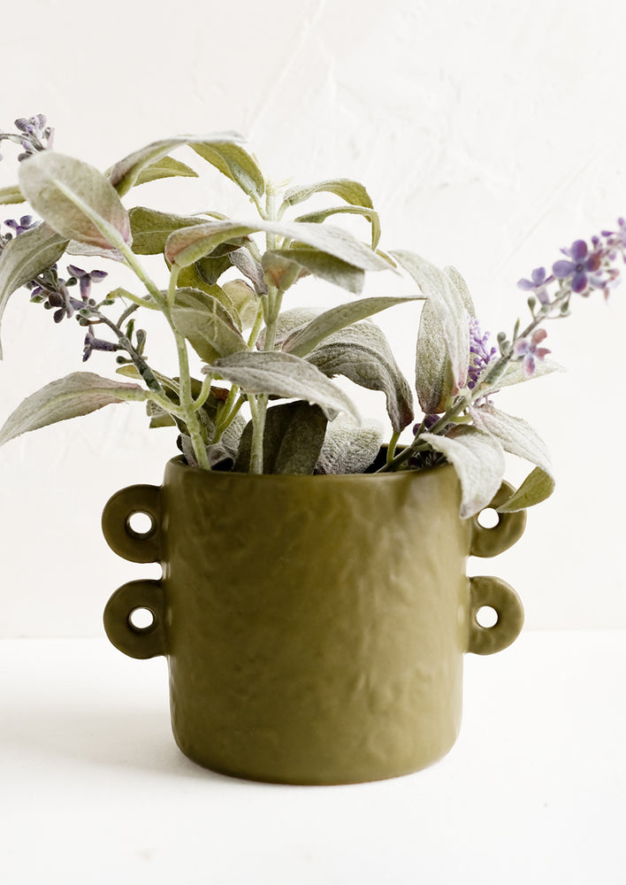2: An army green round planter holding lavender plant.