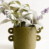 2: An army green round planter holding lavender plant.