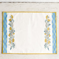 2: A screenprinted floral placemat with turquoise and blue checker border.