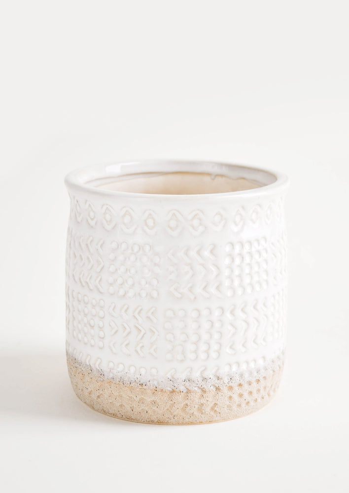 1: Round ceramic planter with glossy white glaze and natural clay exposed at bottom, allover textured tribal pattern