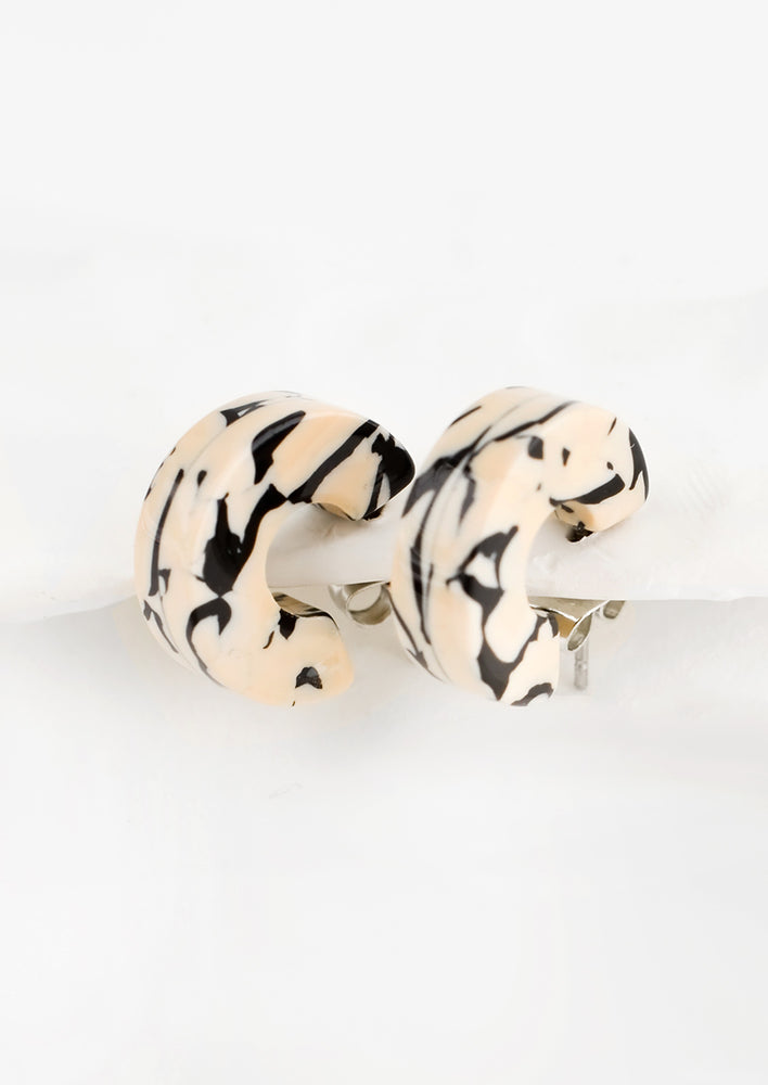 A pair of small acetate hoop earrings in tan and black marble.