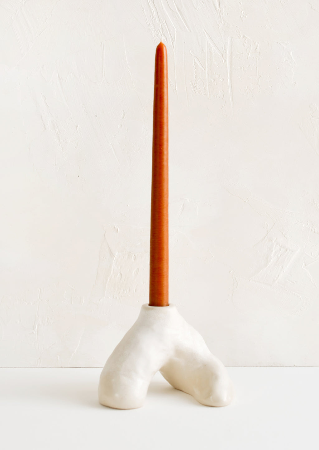 3: A ceramic taper holder in barnacle-like shape with rust colored taper candle.