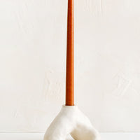 3: A ceramic taper holder in barnacle-like shape with rust colored taper candle.