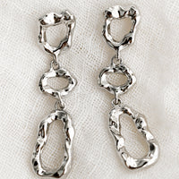 Silver: A pair of silver abstract shape drop earrings with melted metal look.