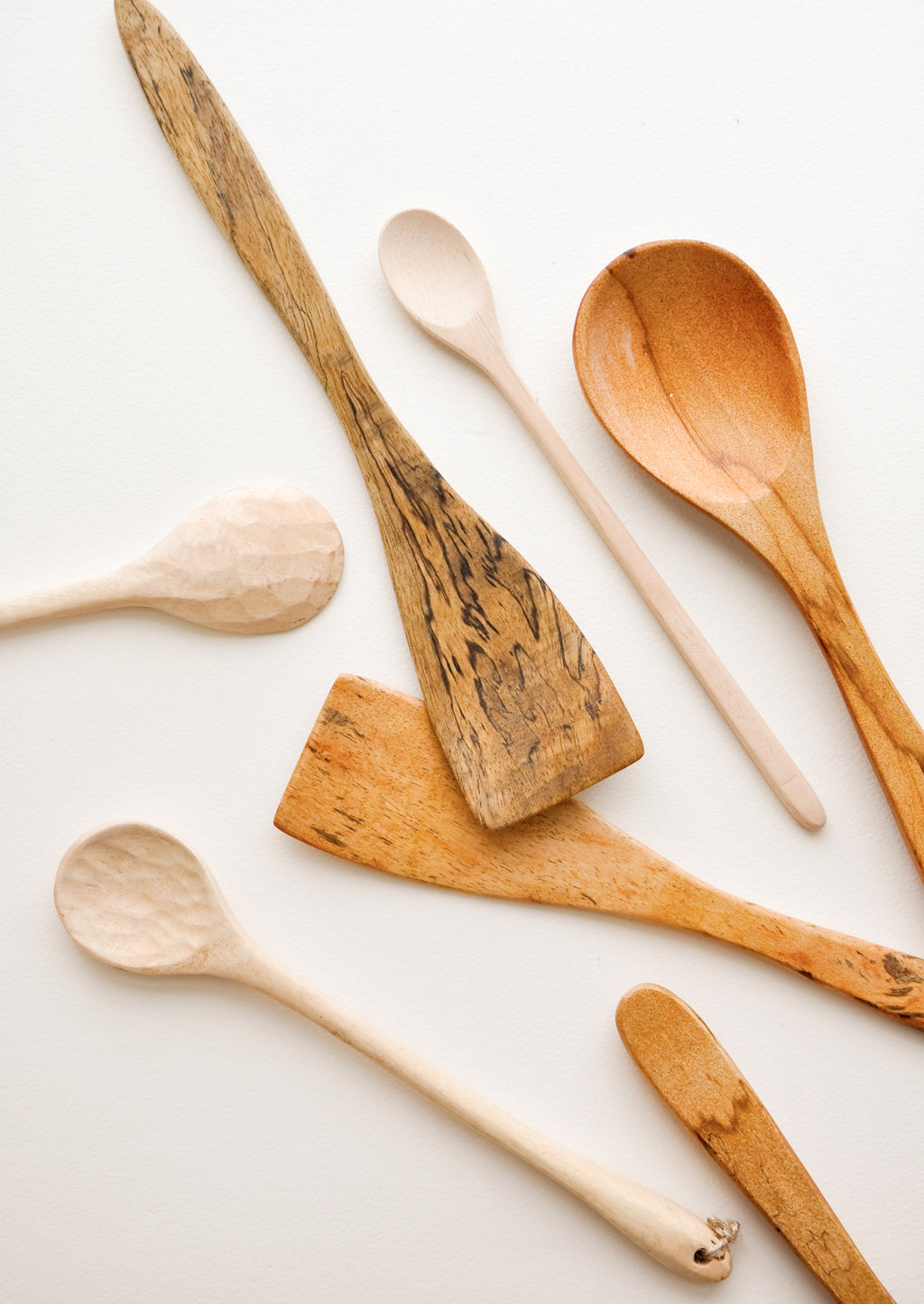 1: Wooden spoons of different colors, shapes, and sizes displayed in a haphazard d fashion.