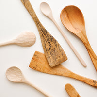 1: Wooden spoons of different colors, shapes, and sizes displayed in a haphazard d fashion.