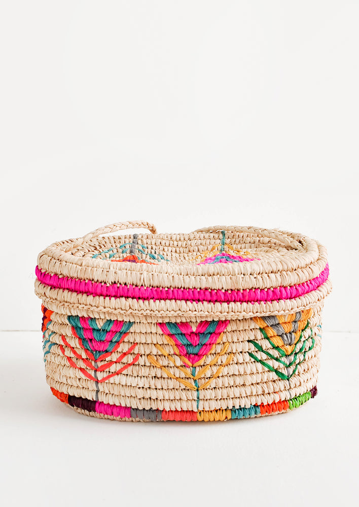 Multicolor: Rounded box style straw bag with neon multicolored flower pattern.
