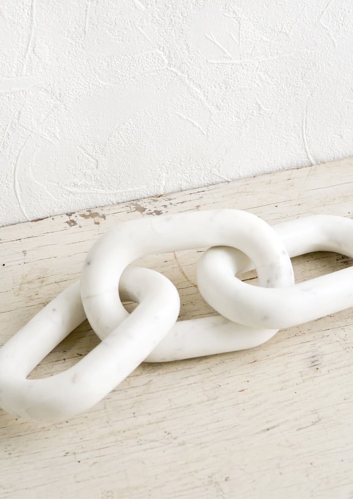 A decorative object made from solid white marble in the shape of three chainlinks.