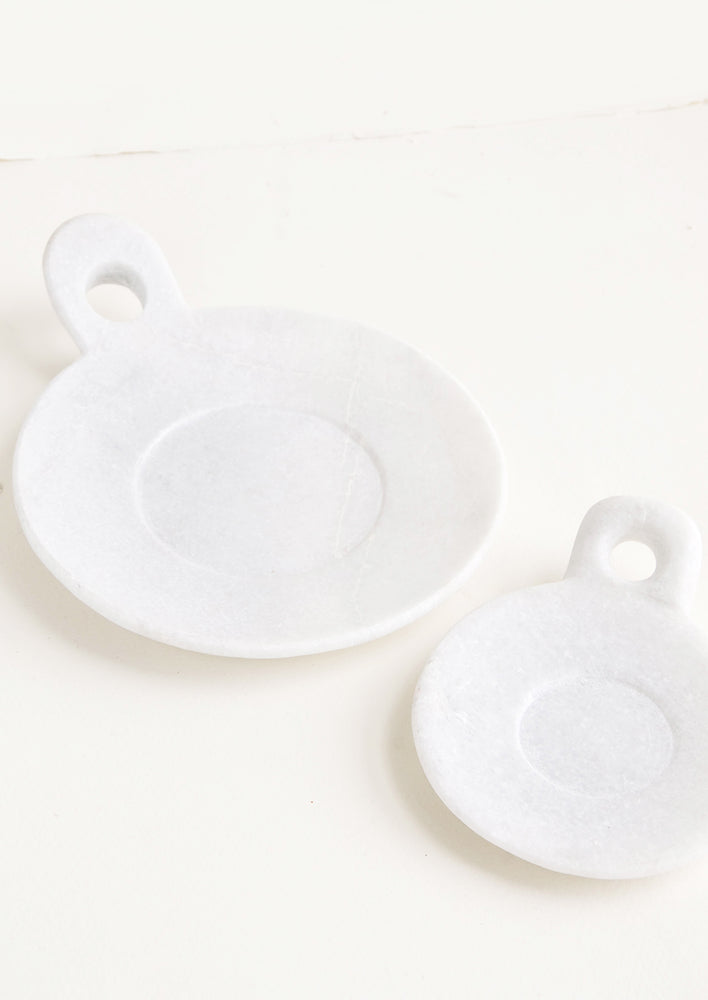 Round marble dishes with circular cutout side handle and circular inset at center