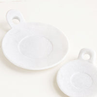 2: Round marble dishes with circular cutout side handle and circular inset at center