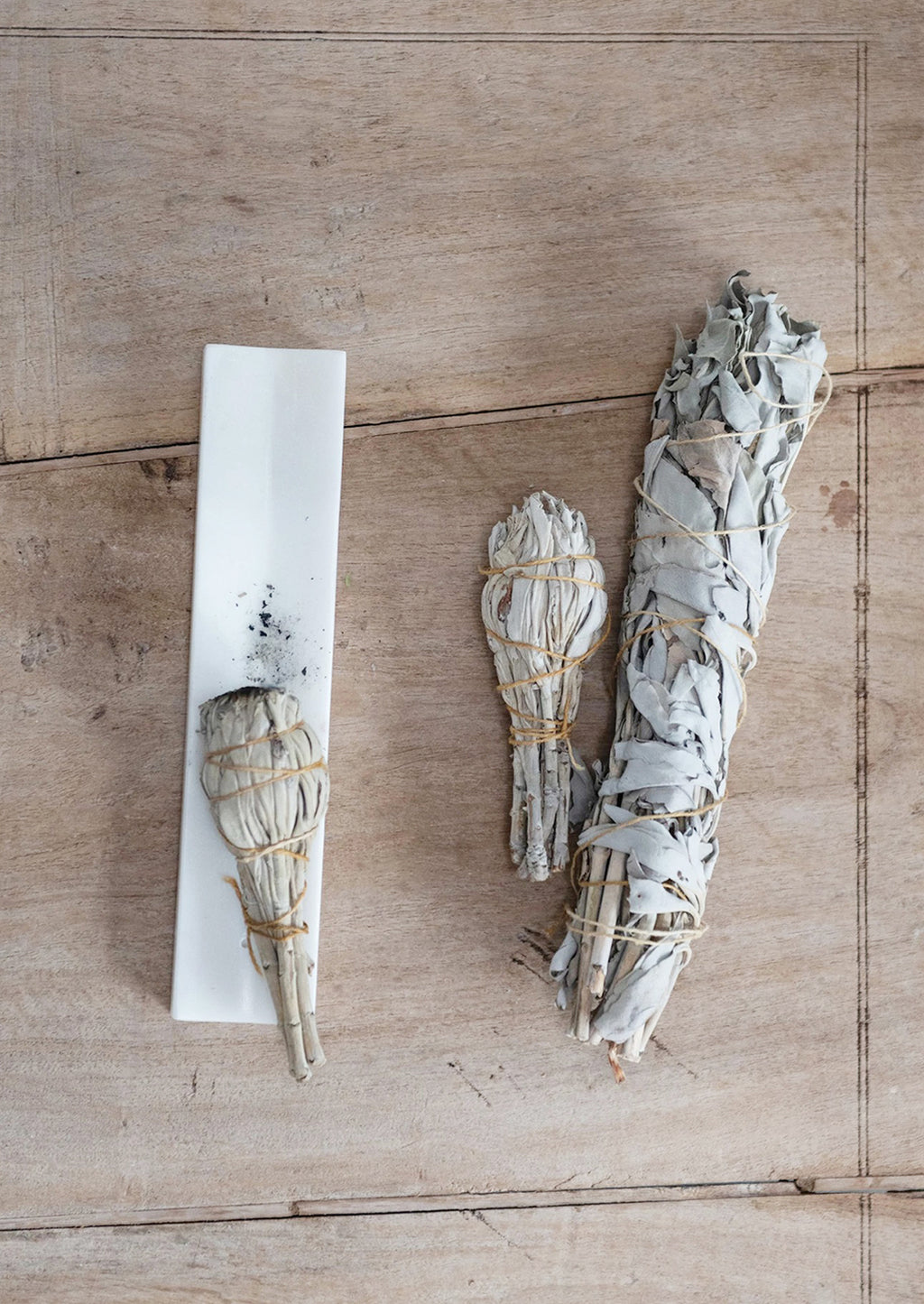 2: A long solid marble incense burner tray, shown with sage smudge bundles.