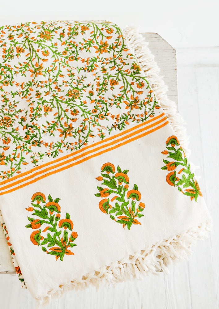 1: Block printed cotton tablecloth with orange and green floral pattern and tasseled edges