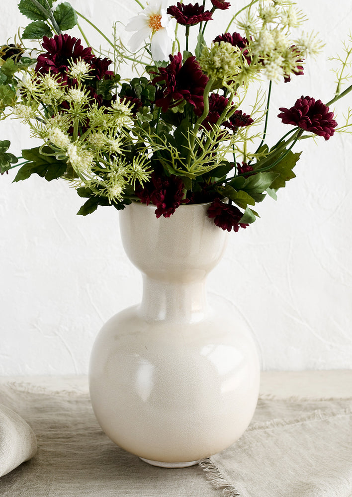 A vase with large bouquet of mixed faux flowers.