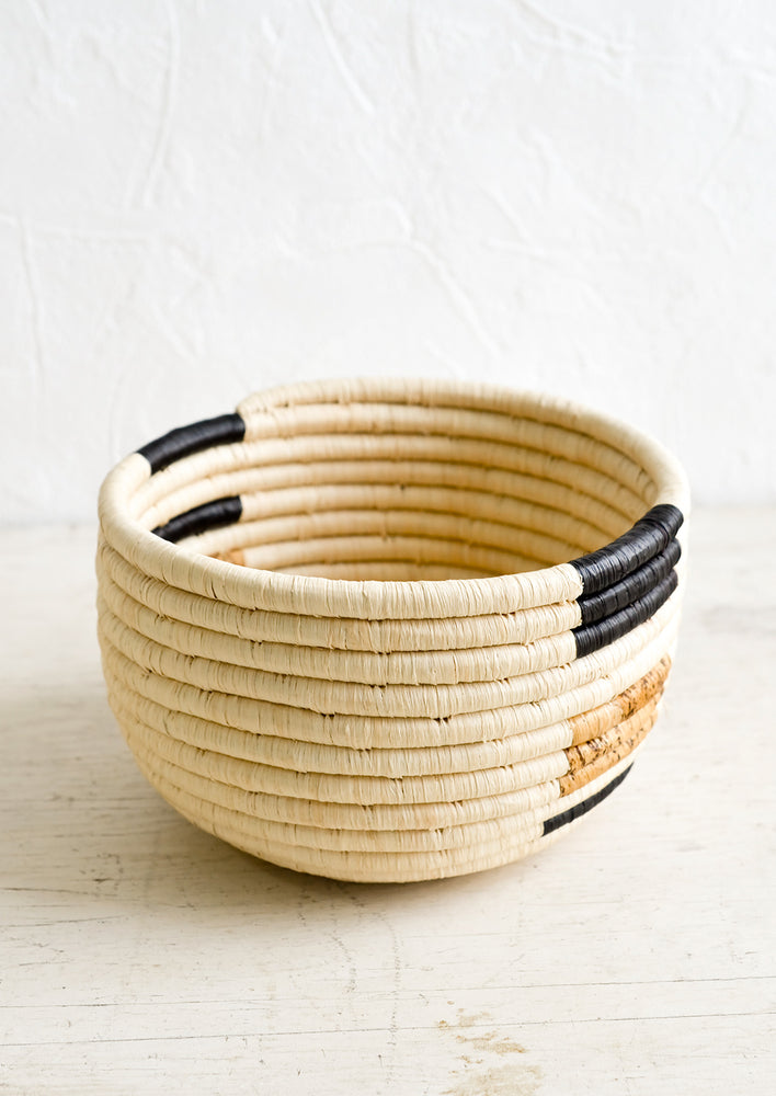 A round catchall basket made from natural woven raffia and banana bark.
