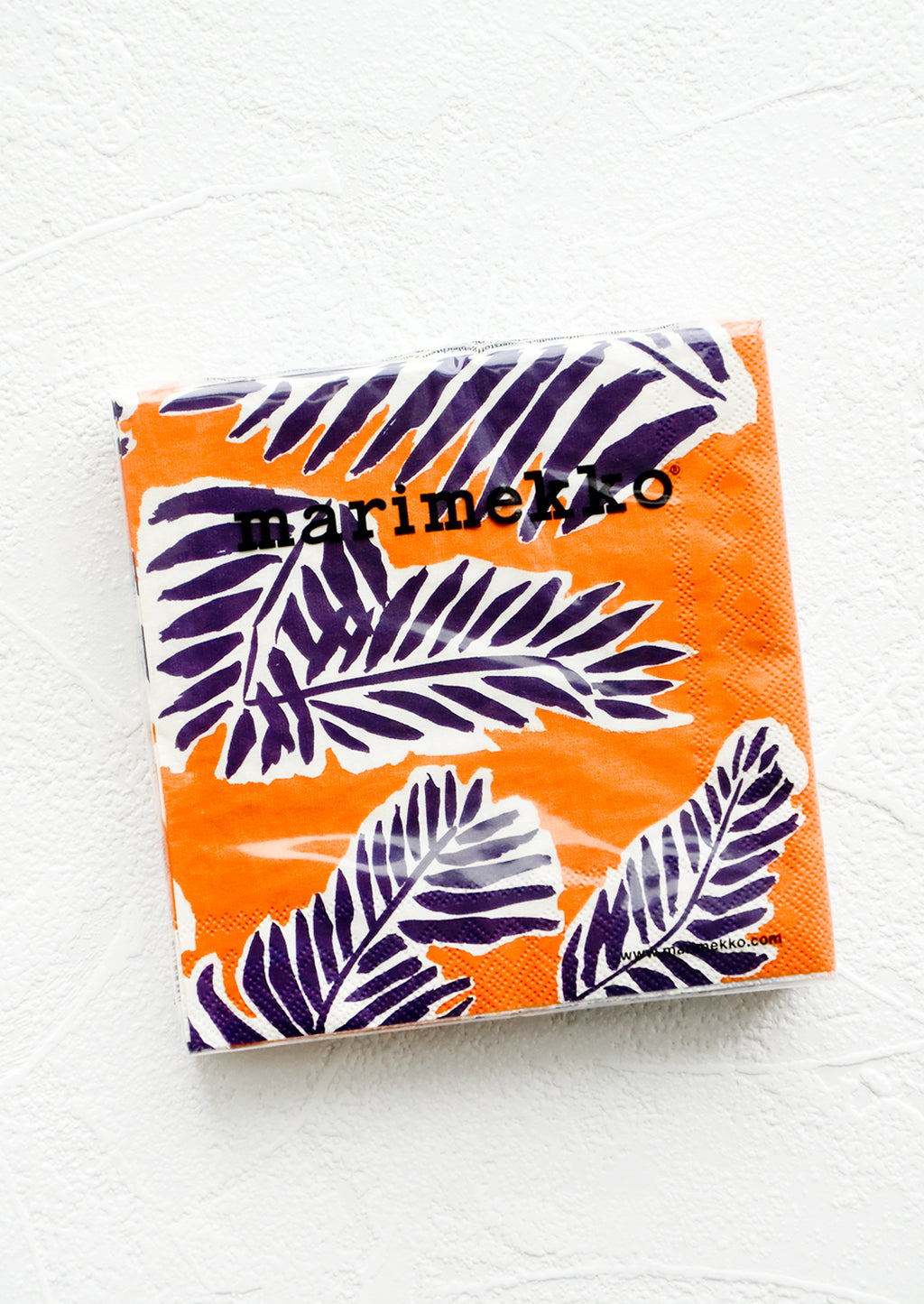 Orange / Aubergine: Packaged disposable paper napkins in square cocktail size with orange and purple leaf print.