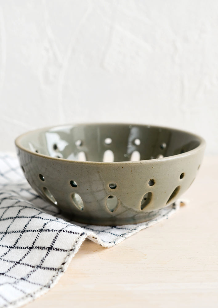 A ceramic berry bowl with drainage holes in khaki.