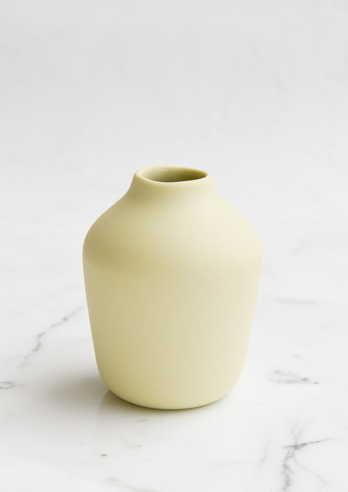 A pale yellow porcelain bud vase.