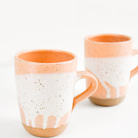 Peach / White: Two ceramic mugs in orange and white with brown speckles.