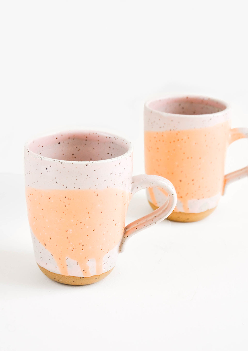 Pink / Peach: Two ceramic mugs in orange and pink with brown speckles.