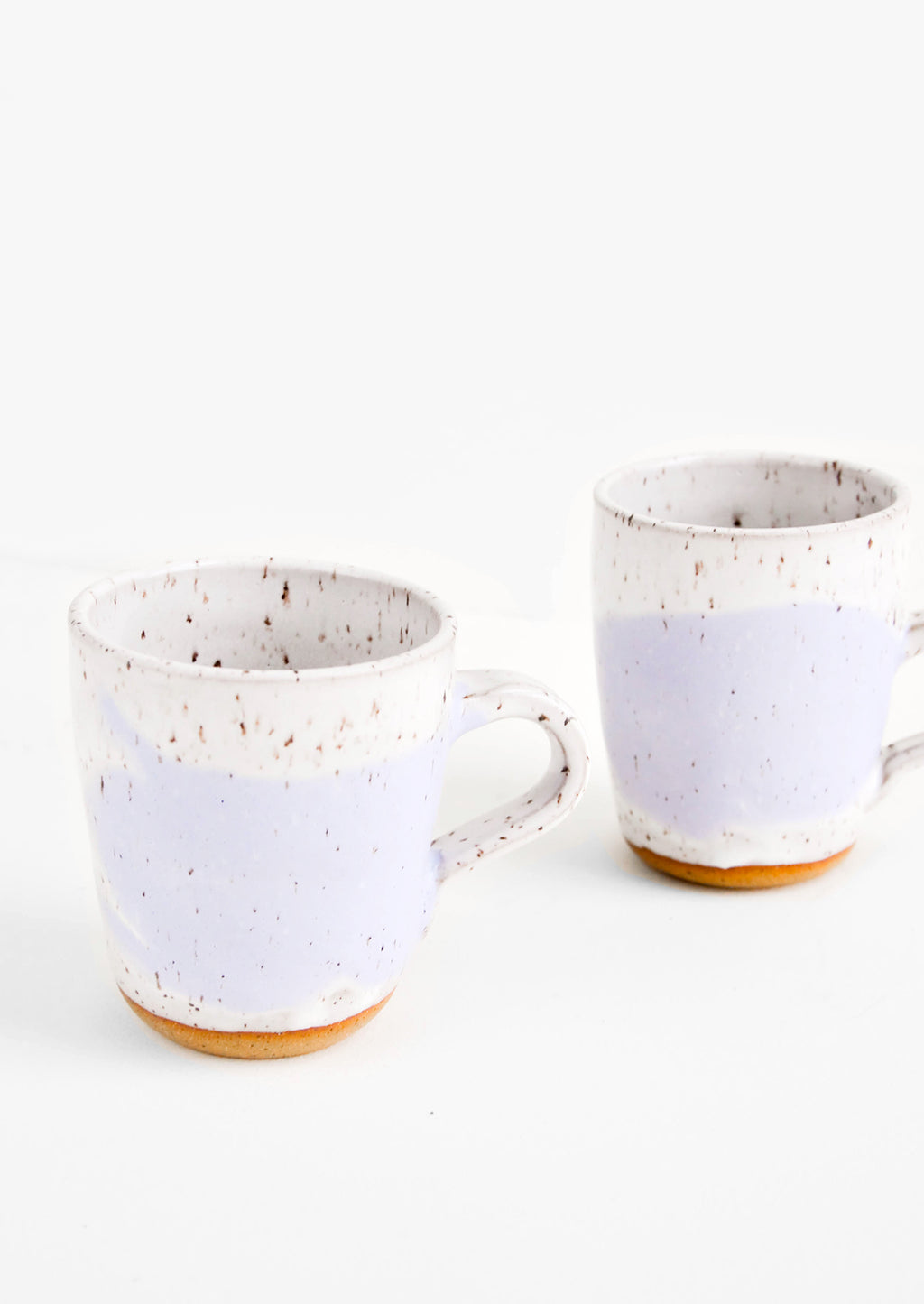 White / Wisteria: Two ceramic mugs in white and purple with brown speckles.