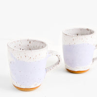 White / Wisteria: Two ceramic mugs in white and purple with brown speckles.