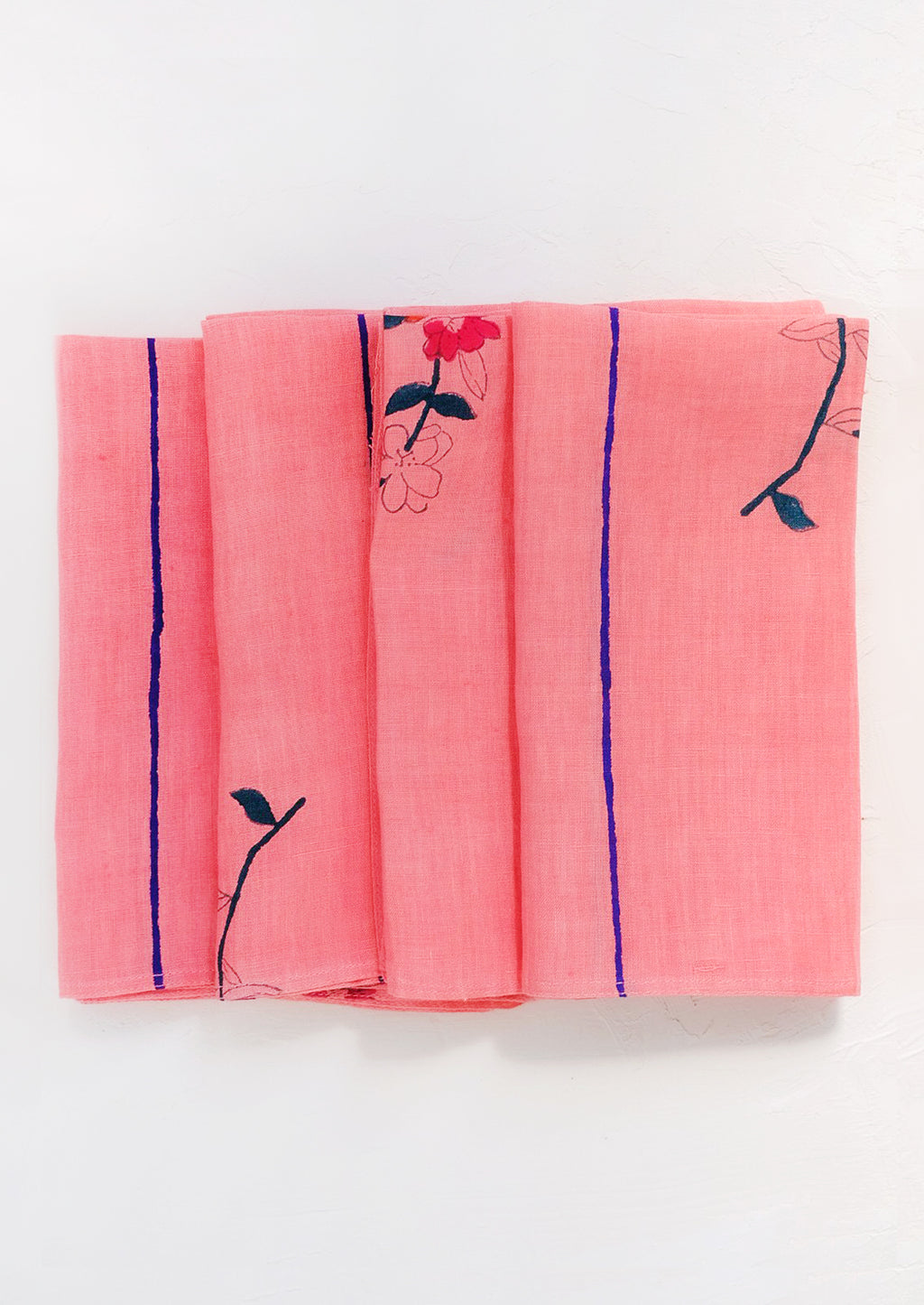 1: A folded pink linen napkin with block printed flowers and stripes.