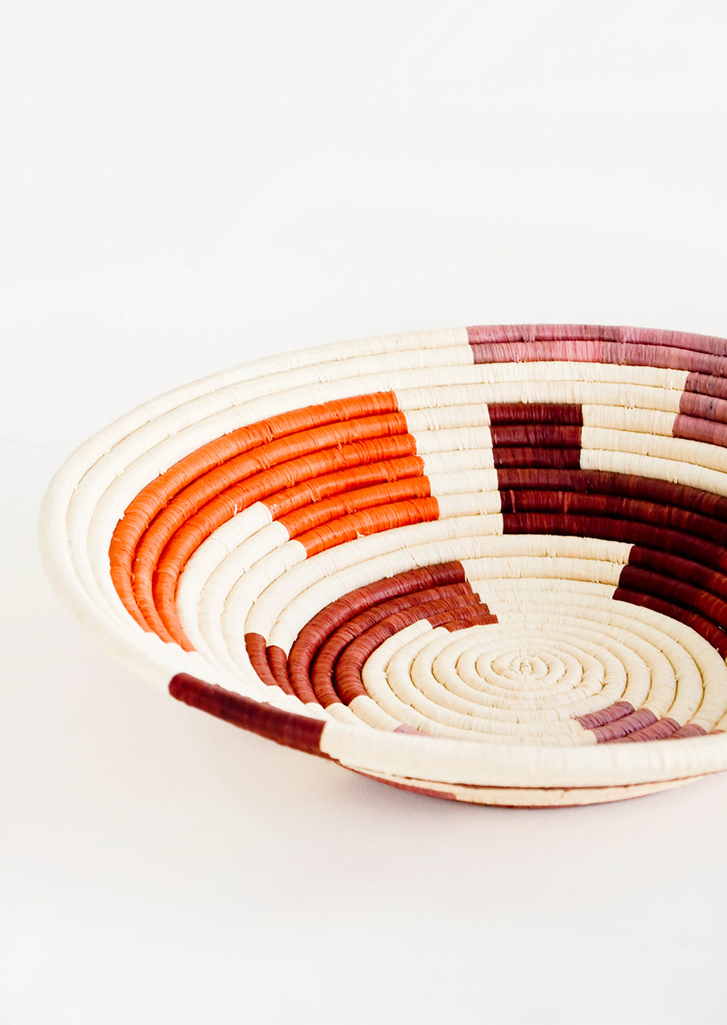 2: Shallow woven raffia bowl with maze print in wine, orange and mauve