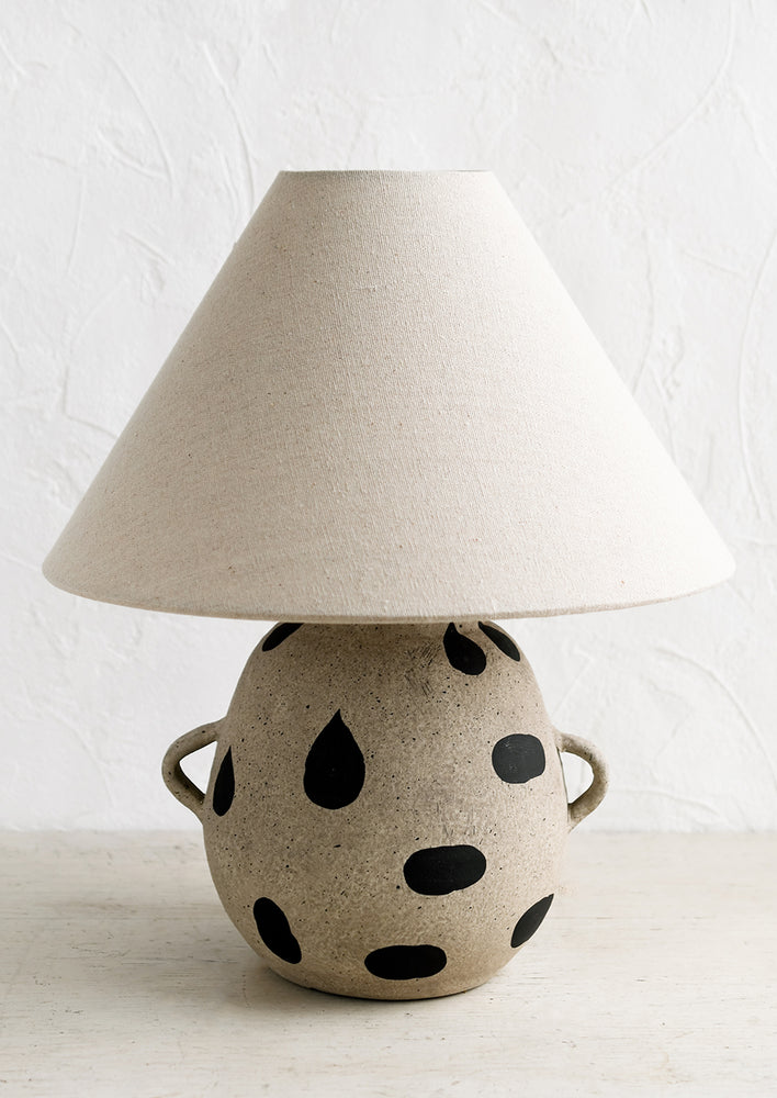 1: A ceramic table lamp with dot print and side handles on base, with tapered linen shade.