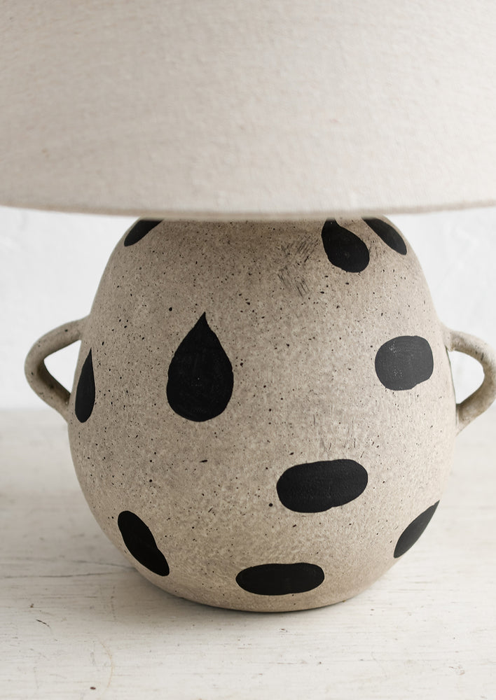 A ceramic table lamp with dot print and side handles on base, with tapered linen shade.