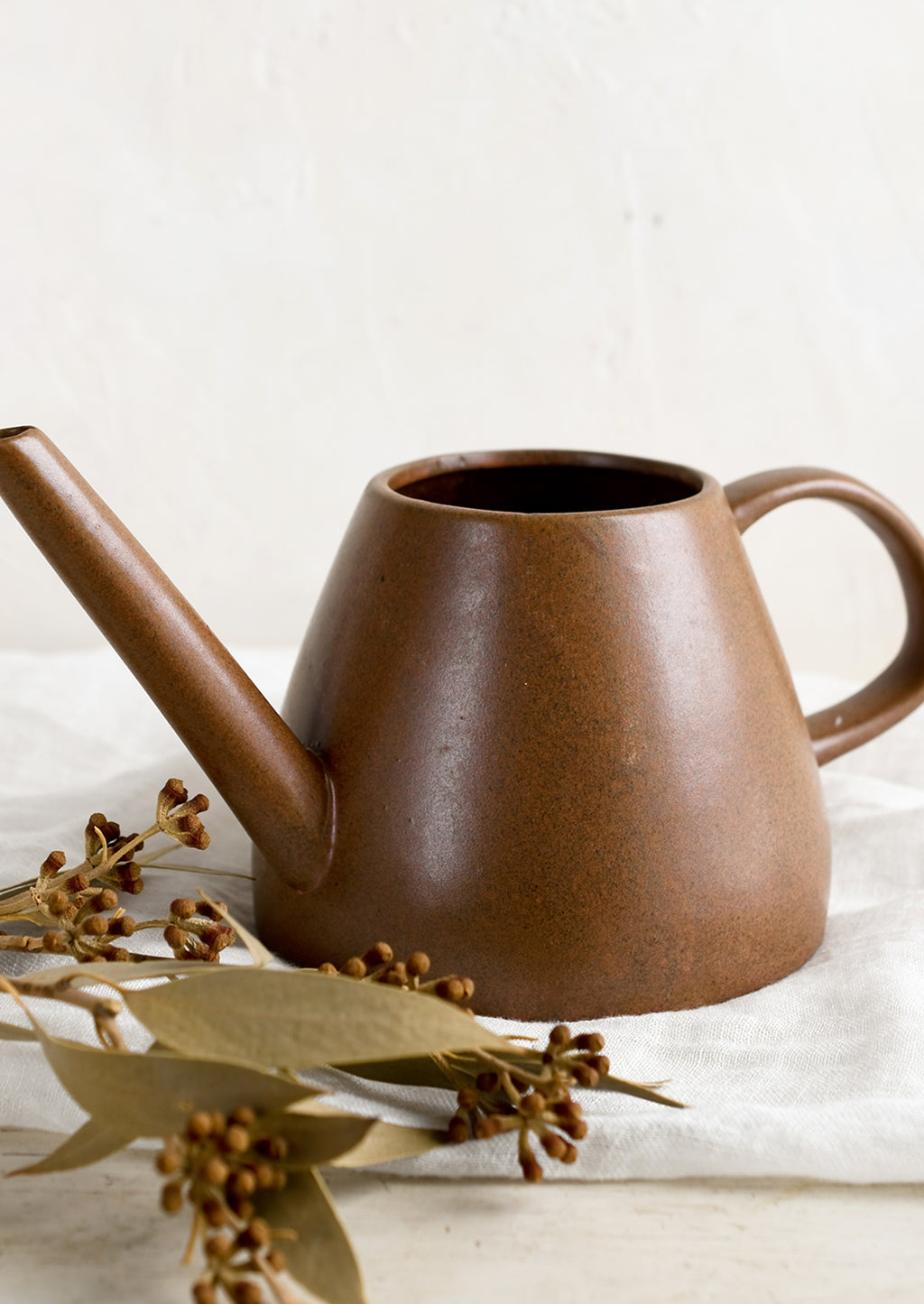 1: A ceramic watering can in brown color.
