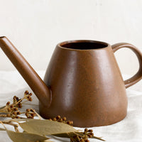 1: A ceramic watering can in brown color.