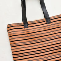 1: A striped canvas tote bag with black leather handles.
