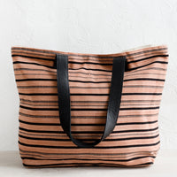 2: A striped canvas tote bag with black leather handles.
