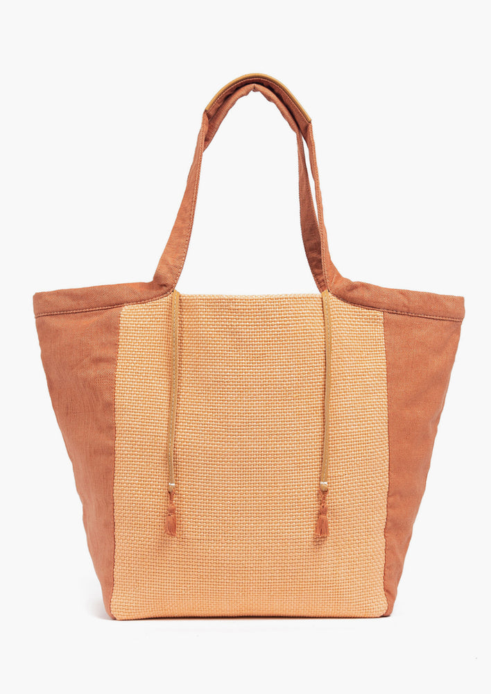 1: A cotton canvas tote bag in peach and terracotta with leather tie detail.