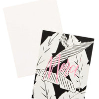 3: Notecard with black and white palm leaves decoration and the word "Merci" in pink, and white envelope.